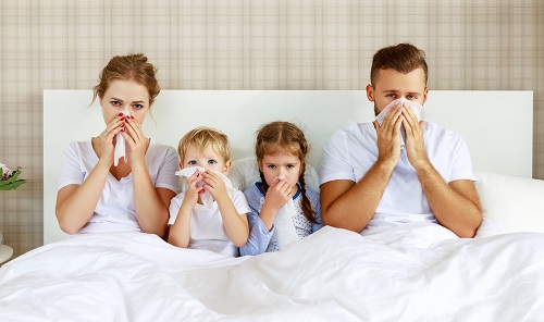 family in bed sick with flu antibacterial spray